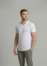 Man wearing a plain white v neck t-shirt and green pants against a gray background from ten10 apparel