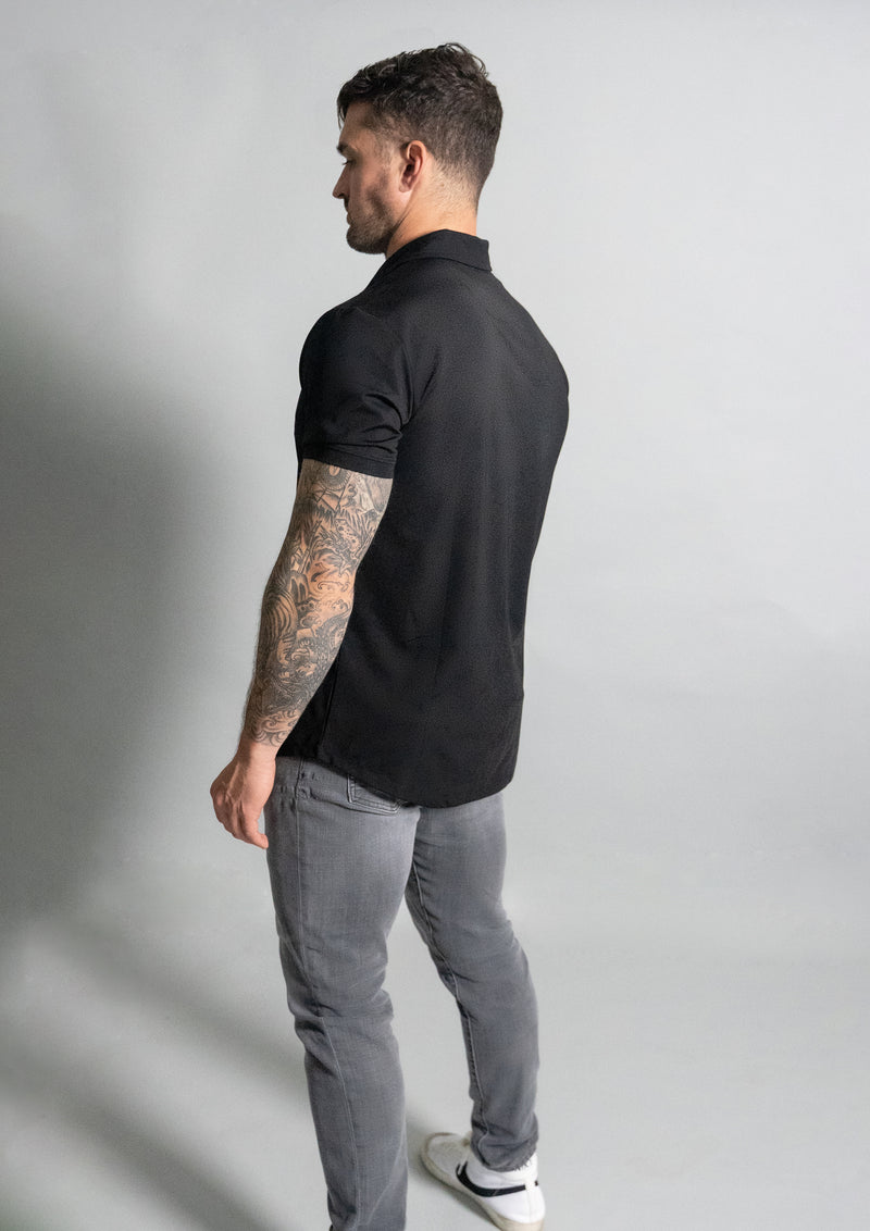 model in black polo from ten out of ten apparel with back towards viewer.
