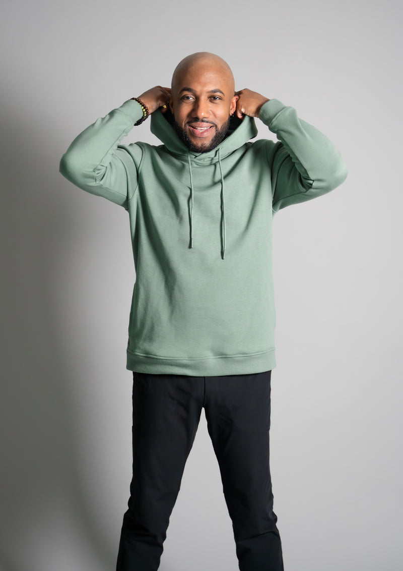 Male model smiling in a de saturated green hoodie from ten10 apparel