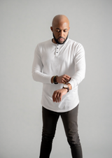 Men's white long sleeve henley with black buttons for an athletic build with a male model looking towards sleeve. Henley from Ten ten apparel