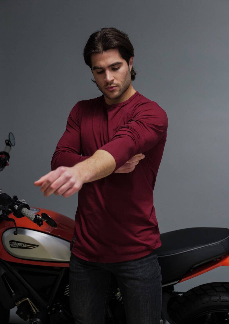 Male model with Ducatti in Ten/10 apparel long sleeve dark red-burgundy curved hem bottom shirt