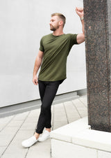 male model in dark green fern shirt leaning next to cinderblock in New Orleans 10 apparel