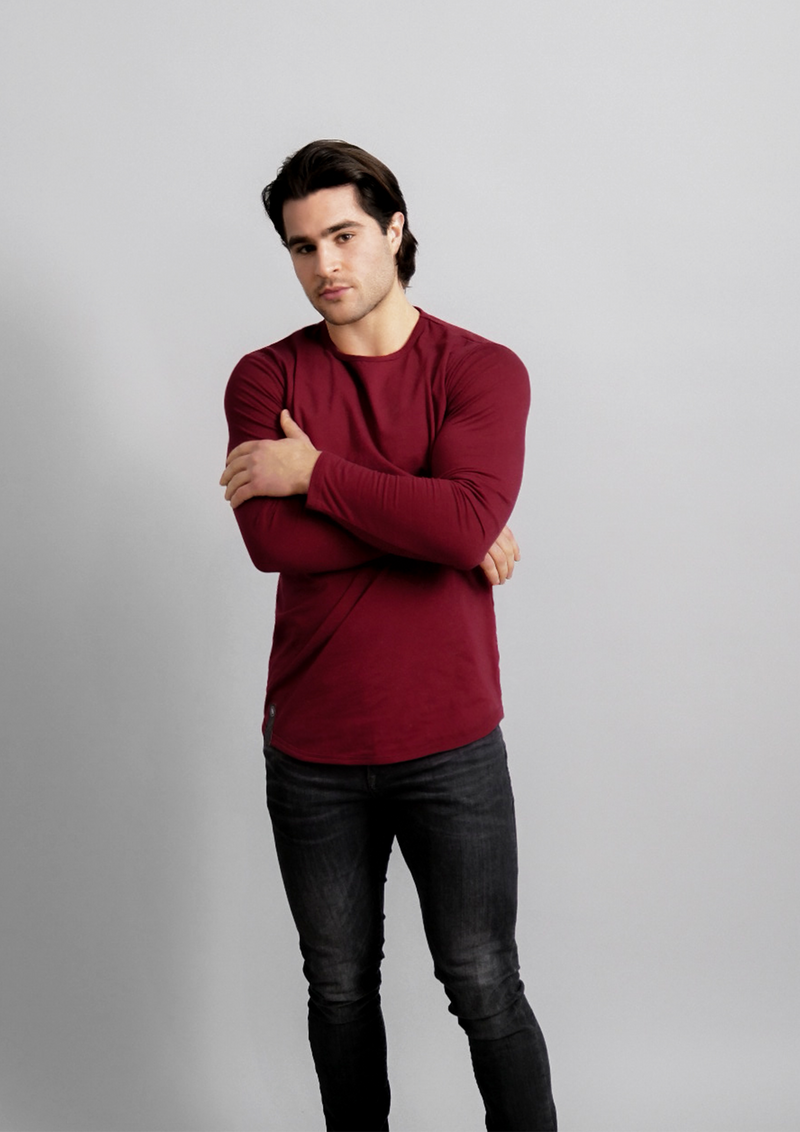 Male model in a dark red mahogany long sleeve ten out of ten dropcut shirt with arms slightly folded