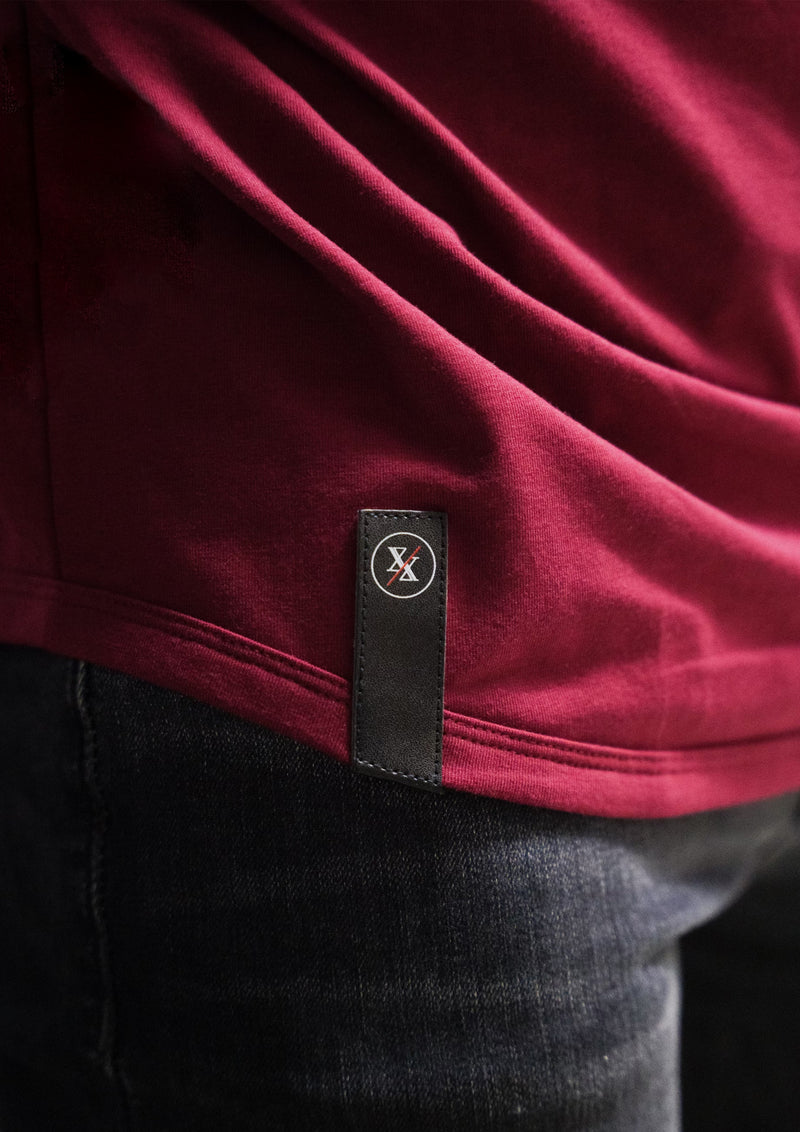 Studio light bottom of a drop cut curved hem of red shirt showing Ten10 apparel logo